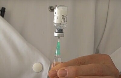 Врач набирает в шприц с пузырьком препарата